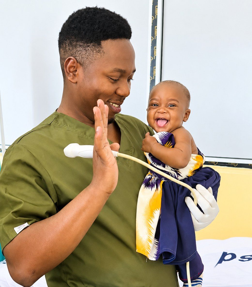 Echo tech holding an ultrasound probe raises his hand to a laughing baby